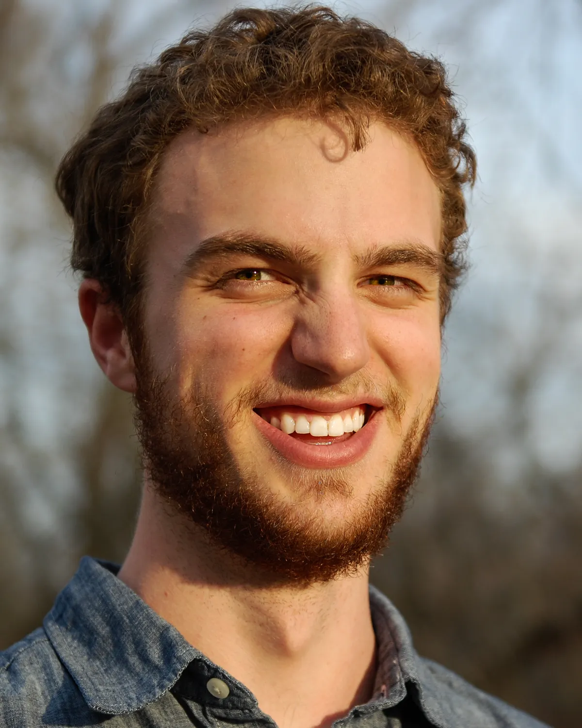 Sean McKeever smiling outdoors in late-afternoon light, wearing a blue chambray shirt.